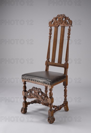 Chair, shells ornament, plant decoration, Camaldolese order, crown motif, Camaldolese monastery Warsaw, Baroque style, CHAIR with turned and carved frame elements, with a padded seat and high backrest, supported by four turned legs fastened with turned links, forming an H link at the bottom, with an additional carved board on the front the shell is enclosed on the sides by U-shaped acanthus leaves, topped with a closed crown. Front legs with carved feet in the form of a claw clamped on a ball, the rear legs angled outward, with ankle feet. The backrest is filled with two profiled slats, with side frames in the shape of slender balusters, a carved top board with decoration similar to the board connecting the front legs. Trapezoidal seat, upholstered with leather covering the frame. Ca. 1700, Gdansk, seating furniture, furniture, height 124.7 cm, width 51.5 cm, depth 52 cm, A wooden chair with a tall, ornate backrest featuring carved scrollwork and turned vertical supports, a dark cushio...