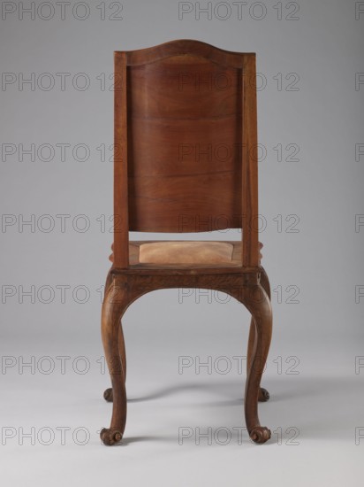 Chair, origin unknown, Rococo style, ca. 1750–1765, Germany. Rococo chair with boarded inlaid backrest depicting a lady in a crinoline surrounded by flowers; rectangular originally upholstered seat supported by cabriole legs. Legs decorated in bas-relief with motifs at the top, including shells on the knees, terminating in volute feet. Frame wavy-cut at the bottom, decorated with acanthus leaves. Seat frame with a wavy outer outline enclosing a padded central section. High backrest with clearance, angular stiles, and a wavy-curved upper section. Inlaid representation on the backrest framed by two intertwining U-shaped ribbons. Ornament: volutes, plant decoration, acanthus, shells, female figures, flowers, ribbon-and-pincer. Furniture type: seating piece. Dimensions: height 115 cm, width 53 cm, depth 63 cm., A wooden chair shown from the back with a tall curved backrest and a slightly padded seat, both in shades of brown; the chair frame and cabriole legs are medium to dark brown wood w...