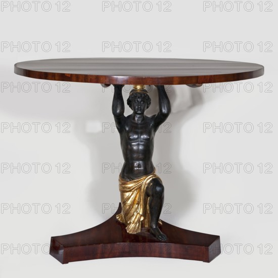 Table, creator unknown, empire style, male figures, circa 1816–1825, possibly Warsaw or Vienna, furniture table, height 81 cm, diameter 110 cm, A round wooden table top in a rich brown color is supported by a dark bronze-toned sculpted figure of a kneeling male with detailed musculature, holding the tabletop above his head; the figure wears a gold-colored draped cloth around his lower body and a small gold-colored headpiece, and the base is a carved wooden plinth in a similar brown tone.