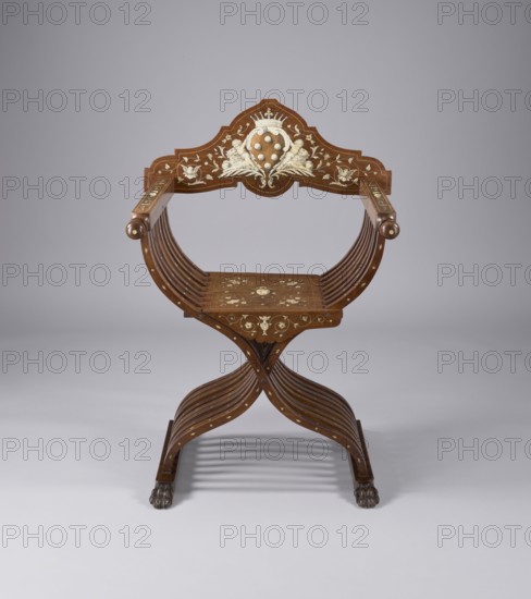Scissor chair, Scissor armchair made of eight pairs of crossed S-shaped slats, connected at the bottom by runners and at the top by armrests, with a board backrest and seat, decorated with ivory inlay. The slats are fastened with a steel rod at the intersection, which, together with the lifting seat and backrest board, enables the structure to be folded and unfolded. The runners are angular, ending in carved animal paws at the front. The armrests are angular, ending in spheres and movable rings. The backrest is roughly triangular in shape, with a wavy outline, and the seat features an apron added at the front. The backrest board features an inlaid Medici coat of arms beneath a seven-baton crown, supported by putti and lions. Decoration around and on the seat is a grotesque twig; the slats are inlaid with rhombuses. Neo-Renaissance style, third quarter of the 19th century, Italy. Piece of furniture seating, height 109.5 cm, width 70 cm, depth 57 cm., A wooden chair with curved arm suppo...