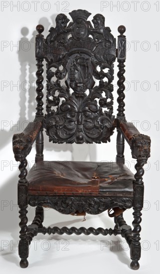 Armchair, origin unknown, neo-Baroque, early 20th century, Central Europe. Carved armchair with a padded trapezoidal seat and a high openwork backrest topped with the Gdansk coat of arms supported by two lions, with the motto NEC TEMERE NEC TIMIDE on the sash below. Straight, spirally turned legs with H binding joints. Straight, narrow frame, wider front, wavy-cut, carved with symmetrical acanthus twigs. Wide central backrest board with a cartouche rollwork with a sailing ship enclosed by a fleshy acanthus twig passing into a mascaron at the bottom; mounted between spiral side rails topped with spheres. Straight, angular armrests with padded rests culminating in a lion mask at the front. Structural elements join the cube. Frame painted black. Seat upholstery on springs, upholstered with brown leather, including the armrests. Resembling Gdansk Baroque. Furniture seating piece. Height 135 cm, width 69 cm, depth 75.2 cm., A dark wooden armchair with elaborate carved details fills the fram...