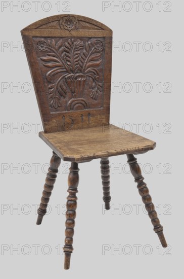 Stool with bas-relief backrest and board seat, on four pearl-turned legs, diagonally inclined. Trapezoidal backrest topped with a segmental arch, decorated with flowers in a vase, with a rosette above, and the date 1511 engraved below. Trapezoidal seat with cut corners and a beveled rim, braced at the bottom with wide claws in which the legs are set. Vases with flowers motif; plant decorations. Early 20th century, Central Europe. Piece of furniture seating, height 99.7 cm, width 50 cm, depth 48.7 cm., unknown provenance., A wooden chair with a carved backrest showing a stylized floral motif in relief, a slightly arched top edge with a carved flower, and a flat seat with a worn surface; the chair stands on turned spindle legs with rounded, beaded detailing. The visible colors are brown tones in the wood with darker brown carving accents and a light gray background.