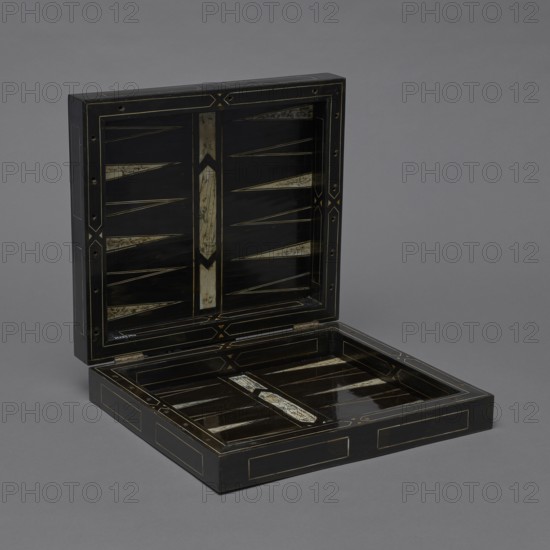 Chess, mill and backgammon box; maker, games; flower vases; chess; ; plant decoration; baroque style; landscapes; backgammon; animals; birds; checkers; 1680s; France; furniture; game furniture; height 9 cm, width 37 cm, depth 32.8 cm, The image shows an open rectangular box with a hinged lid displayed against a uniform gray background; the box is primarily black with decorative inset panels and narrow linear accents in a muted gold and ivory tone, featuring elongated triangular inlays and central vertical inlays with marbled ivory-like patterns, and the interior surfaces reflect light creating glossy dark areas alongside the gold and ivory detailing.
