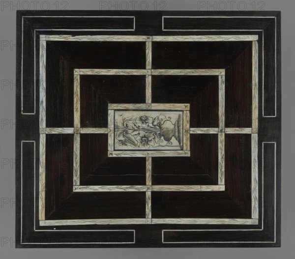Chess, mill and backgammon box; maker, games; flower vases; chess; ; plant decoration; baroque style; landscapes; backgammon; animals; birds; checkers; dated 1680s; France; furniture; equipment; game furniture; height 9 cm; width 37 cm; depth 32.8 cm, The image shows a square decorative panel with a geometric pattern of concentric rectangular frames and crossbars creating smaller rectangular compartments, featuring dark brown wood sections bordered by lighter cream-colored inlaid strips with subtle carved or etched linear designs; the center contains a small rectangular panel with a floral motif rendered in cream and brown tones, showing stylized flowers and curving stems; the outermost border is a thicker dark brown frame with inset cream lines, and the background surrounding the panel is a uniform gray.