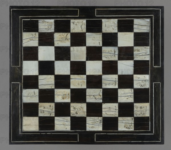 Chess, mill and backgammon box, games, flower vases, chess, plant decoration, baroque style, landscapes, backgammon, animals, birds, checkers party game, 1680s, France, furniture, equipment, game furniture, height 9 cm, width 37 cm, depth 32.8 cm, A square board with a checkered pattern of alternating dark brown and off-white tiles, framed by a wide dark brown border with lighter inset lines; the off-white tiles show faint natural veining and some irregular darker streaks while the dark brown tiles appear solid and smooth; the border has worn lighter edges and narrow rectangular insets, and the background around the board is a neutral gray.