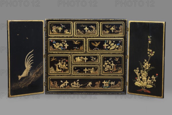 Cabinet, origin unknown, chinoiserie decoration with flowers, birds, trees, rocks, genre scenes against a landscape background, buildings, Chinese figures, bridges, geometric ornament, plant decoration; ca. 1725; furniture storage cabinet; height 76 cm, width 85.5 cm, depth 41.5 cm, A decorative cabinet with open doors revealing a grid of drawers, all finished in black with gold-painted landscapes, birds, floral motifs, and ornamental borders; the left door shows a gold bird with long tail feathers descending over a dark brown textured area against black, while the right door displays a gold floral spray with small red and blue accents at its base; the central drawer panels feature gold scenes of birds, plants, rocks, and small decorative inlays in colors including blue, red, turquoise, and pale green, all set within gold-lined rectangular frames on a black background, and the cabinet edges have gold trim; the overall color palette includes black, gold, brown, red, blue, turquoise, and...