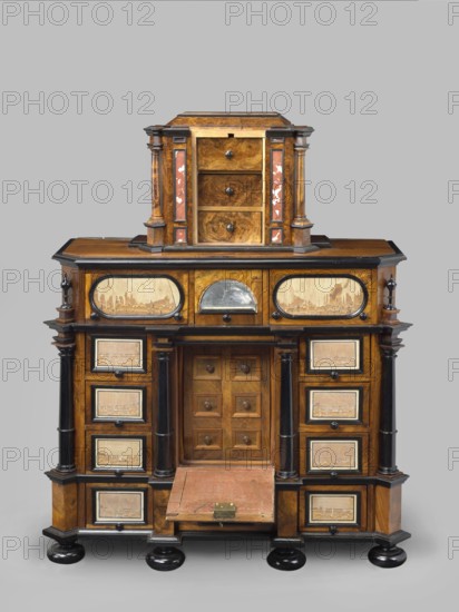 Cabinet, baroque, columns, birds, early 18th century, Southern Germany, possibly Augsburg, piece of furniture storage piece, height 114 cm, width 92 cm, depth 41 cm, creator unknown, provenance includes repossession., A wooden cabinet with a tiered form stands against a plain gray background, featuring warm brown wood tones with darker brown and black accents, and touches of reddish inlay on the upper section. The piece has a smaller upper chest with three drawers flanked by columns and decorative panels, sitting atop a larger lower case with a central recessed compartment behind a small door and a drop-front panel covered in worn red material with a metal latch. The lower section includes a group of drawers on each side framed by dark columns and rectangular panels that show lighter wood inlays with textured surface details. The cabinet rests on rounded black bun feet and shows polished wood grain, contrasting black trim, and small round wooden knobs on many of the drawers.