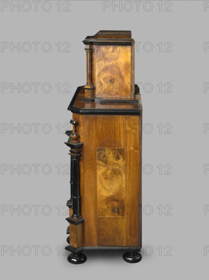 Cabinet, baroque style, columns, birds, early 18th century, Southern Germany Augsburg?, piece of furniture, storage piece, height 114 cm, width 92 cm, depth 41 cm, A wooden cabinet shown from the side with a warm brown wood grain and darker brown and black accents, featuring turned columns and ornamental moulding, a stepped top section, a flat horizontal surface, and rounded black feet against a neutral gray background.