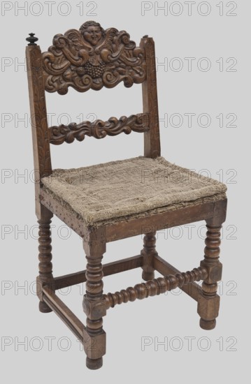 Chair, putti, baroque style, plant decorations, 2nd half of the 17th century, Europe, seating furniture, height 99.5 cm, width 51.5 cm, depth 48.5 cm, An antique wooden chair with a carved backrest featuring a central humanlike face and ornate scrollwork, a carved horizontal slat below with flowing decorative motifs, turned front legs and stretchers with rounded, beaded shapes, a woven rough-textured seat covering that appears frayed at the edges, straight rear legs, and a small finial atop one rear post; visible colors include brown tones in the wood, beige in the woven seat, and a light gray background.