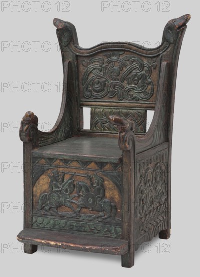 Armchair, wickerwork ornament, battle scenes, knights, plant ornament, dogs, ca. 1500 or 1st half of the 16th century, Sweden, Norway, piece of furniture, seating piece, height 112 cm, width 75 cm, depth 58 cm, An ornately carved wooden chair with a high back and raised armrests featuring carved animal head finials, finished in dark brown with green and muted gold accents, a few areas showing worn reddish-brown underlayers; the backrest displays intricate interlacing carved motifs in dark brown and green, the seat is flat and dark brown, the front panel shows a carved scene of mounted figures in profile with shields and raised weapons set against a muted gold background, the side panels continue with interlaced and figurative carving in dark brown and green, and the chair rests on short square legs with a small worn dark brown footstool-like projection at the front.