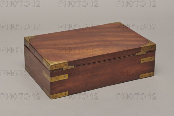 Painter's cassette, Travel painter's cassette, cuboid mahogany box with corners of body and lid reinforced with recessed brass sheets. At the bottom of the body a drawer is blocked by a brass pin inserted from above. Interior front has a row of compartments wider in the middle, square on the sides; behind them two removable containers — an upper one with five compartments three wide, separated by narrow ones and a lower flat container with round sockets for faience paint vessels. Includes a steel pen holder; nine paintbrushes three flat, six round, various numberings, from makers including Pelikan and Z. Dudek Warszawa; five cylindrical glass containers; eight porcelain bowls signed Cmielów / MADE / IN POLAND; a set of watercolors 54 pans; a stick of black Chinese ink; and a resin stick. Bottom of the body is backed with green cloth. Inside the lid is a cardboard and red leather file folder closed with two small brass bolts. Lock is a mortise lock with two sliding hook bolts; lock plat...