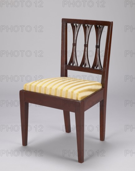 Chair, classicism style. Classicist chair with a trapezoidal padded seat insert cushion and a rectangular openwork backrest filled with three lamellas, supported by four angular legs — front ones straight, rear ones arched outward. Frame painted to imitate mahogany. Circa 1800, Poland . Piece of furniture, seating piece. Height 59 cm, width 36 cm, depth 36 cm., A wooden chair with a dark brown finish showing a rectangular backrest that has three decorative vertical cutouts with curved shapes, a square seat upholstered in striped fabric, and four straight tapered legs; the upholstery displays alternating stripes of yellow and a paler yellow or cream, and the background is a plain light gray.