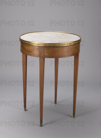 Table, classicism style, geometric ornament, round mahogany table with a white marble top enclosed by a brass gallery, supported by four slender, straight legs tapering downwards. Entire table polished. Legs finished with knuckles at the top and brass rollers with angular clamps at the bottom. Drum-shaped frame contains a drawer with a lock. Stone slab chiseled on the underside. Upper frame supporting the top is chiseled at points of varying thickness. Cast gallery gilded with amalgam. Date: 1790–1810, France . Furniture, table. Height 77 cm, diameter 57.6 cm., A round wooden side table with a white marble top rimmed by a decorative brass band sits against a neutral gray background; the table has a warm brown wood finish on its apron and four tapered legs that end in small brass caps on casters, and the visible colors include brown, white, brass gold, and shades of gray.