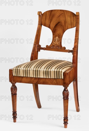 Chair, acanthus ornament, Biedermeier style, palmettes ornament. Mahogany chair with a padded seat removable cushion and a board backrest. Front legs straight, turned in the form of a baluster; rear legs sabre-shaped. Trapezoidal seat, slightly bulging at the front. Wide side frames embrace the seat cushion. The cushion rests on a pine frame, upholstered in green-striped fabric. The backrest consists of angular, S-shaped side stiles, a lower crossbar, and a rounded central board placed between them, narrowed at the bottom, straight in line with the back. The backrest stiles are widened in the lower section, ending at the top with a forward-curved volute. Polished frame enriched with carving—acanthus leaves on the upper part of the front legs, antemion and symmetrical S-shaped beams at the bottom of the backrest boards, scrollwork at the ends of the backrest crossbars. 1830–1840, Warsaw?, Poland. Seating furniture; furniture. Height 92 cm, width 51.4 cm, depth 56.5 cm., A wooden chair w...