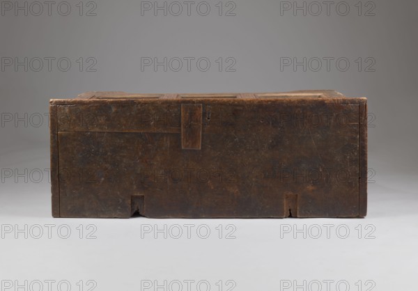 Chest, Gothic style, floral and geometric ornament, repossession, CHEST with straight sides and front forming console legs at the bottom, with a flat lid, decorated on the pseudo-frame of the front with an engraved decoration featuring a dry thistle motif, with a darkened background. Panels and sides are smooth, without decoration. The lid is framed on the sides and front with profiled frames forming the rim. Board walls, back and front are attached to the body, fastened with dowels. Inside, on the left side of the box. Steel fittings, secondary — steel lock, applied, without a cup, strap-eye hinges, fastened with forged nails. Dated 1500–1520. Place of origin possibly Bavaria, Lesser Poland, Central Europe. Furniture; storage furniture. Height 80.5 cm, width 159 cm, depth 60 cm., A rectangular wooden box with a worn, dark brown surface sits centered against a smooth gray background and a light gray floor; the box shows scratches and small chips, visible joints and a few rectangular cu...