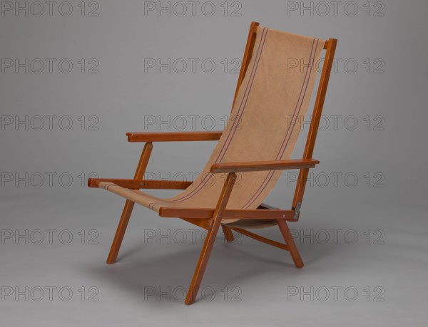 Deckchair, Polish Timber Industry, Czerski and Jakimowicz Lviv; furniture factory; 1929–1939,  furniture factory; lounge furniture, beach furniture, garden furniture, folding. Deckchair constructed from two different sized rectangular frames: the backrest smaller and the seat larger, connected by hinges, with canvas stretched over them. Frame elements except the turned rear leg connector and the doubled front seat stile are angular. The seat frame is supported on its shorter sides by two folding legs connected by a connector, the front extended into armrest supports. Armrests have hinges adjustable in three positions. Salmon-colored canvas fabric with vertical orange stripes framed by narrow blue stripes; attached to the underside of the upper backrest frame and the rear seat frame, sandwiched between the two front seat frames. Originally equipped with a separate footrest. 1938–1939, Lviv; seating furniture, piece of furniture. Height 84.2 cm, width 58.5 cm, depth 115.5 cm., A wooden f...