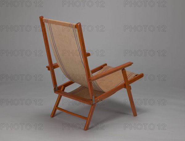 Deckchair, Polish Timber Industry, Czerski and Jakimowicz furniture factory ; 1929–1939,  furniture factory author; lounge, beach, and garden folding deckchair constructed from two different sized rectangular frames: backrest smaller and seat larger connected by hinges, with canvas stretched over them. Frame elements except the turned rear leg connector and the doubled front seat stile are angular. Seat frame supported on its shorter sides by two folding legs connected by a connector, the front extended into armrest supports. Armrests have hinges adjustable in three positions. Salmon-colored canvas fabric with vertical orange stripes framed by narrow blue stripes; canvas attached to the underside of the upper backrest frame and the rear seat frame, sandwiched between the two front seat frames. Originally equipped with a separate footrest. 1938–1939, Lviv; seating furniture; height 84.2 cm, width 58.5 cm, depth 115.5 cm., A wooden folding chair with a fabric seat and back is shown from ...