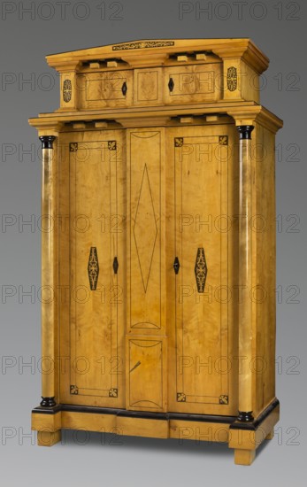 Wardrobe, Repossession provenance. Architectural elements. Biedermeier style. Plant decoration. Two-part wardrobe with straight sides and front, two storeys upper one low, narrower closed with double doors, supported by four block legs; birch veneered, inlaid, polished. Lower part framed in front corners with small columns missing, topped with a simple profiled cornice with cubes. Altarpiece features a triangular, flattened pediment. Door leaves have wide slatted doorstops, divided by a double black vein into rectangular fields with cubes in the corners filled with rosettes, and in the center with inscribed elongated dark hexagons decorated with a light, stylized floral ornament. Analogous decoration on the altarpiece pilasters. Structure, except for the framed back with two panels, is boarded. Base leaves reinforced on the inside with two tacks. Inside back contains a hanger with eight pins and a bar. Steel fittings: double-bolted applied locks; overlay bolts, pintle hinges. Circa 183...