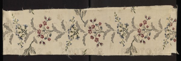 Fabric fragment, Repossession provenance. 18th-century silk fragment, patterned broché silk with metal threads. Background: simple weave with a rep structure, subreport-lisére; brocading with pale and dark blue, multiple sea blues, celadon, white, pale paint green, light and dark pink, apple green, grass green, and silver braided lamella threads. Design: branches of various roses and cornflowers forming a vertically rising, symmetrically branching column with silver leaves between the branches. Zonal brocades, grosgrain background, and fine lisére patterns suggest English influence typical of the 1740s. Date: 2nd half of the 18th century. Place of origin: France. Dimensions: height 114 cm, width 25 cm. Materials: silk, metal threads. Classification: patterned fabric fragment, Gros de Tours liséré, broché., A long strip of pale beige fabric with a repeating floral and ribbon motif running horizontally, showing a few sprigs of small rounded flowers in shades of red and blue with green le...