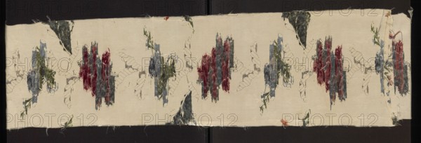 Fabric fragment, 18th-century silk fabric fragment with metal threads; patterned floral broché in Gros de Tours liséré. Background: simple weave with rep structure and subreport-lisére; brocading in pale and dark blue, several shades of sea blue, celadon, white, pale paint green, light and dark pink, apple green, grass green; silver braided thread and silver lamella. Design: vertically rising, symmetrically branching column of branches with various roses and cornflowers, with silver leaves between branches. Zonal brocade, grosgrain background and fine liséré patterns suggest English influence characteristic of the 1740s. Date: 2nd half of the 18th century; place of origin: France. Dimensions: height 114 cm, width 25 cm., A long horizontal strip of fabric with a light beige background features a repeating pattern of roughly vertical textured clusters in shades of red, blue, gray, and green, connected by faint outlined leaf-like shapes in a darker neutral color; there are small scattered...