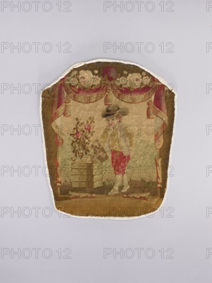 Three tapestry armchair covers, varietals, provenance, floral ornaments, genre scenes, interior furnishings, garlands, furniture upholstery, decorative fabrics, tapestries. Scenes: a boy sitting on a hillock playing a flute, b boy watering flowers, c girl sitting on a hillock. 2nd half of the 18th century, Aubusson; fabrics; height 27.5 cm, width 35 cm., A worn textile fragment with a rounded top set against a light gray background, showing a faded scene woven in muted tones of brown, beige, pink, red, green, and cream; the upper area features a decorative swag and floral border in pink, cream, and brown, while below a figure wearing a dark hat and a red garment stands next to a planter of pink flowers atop a rectangular base, with additional curtain-like drapery in pink and brown framing the scene and a brown ground along the bottom.