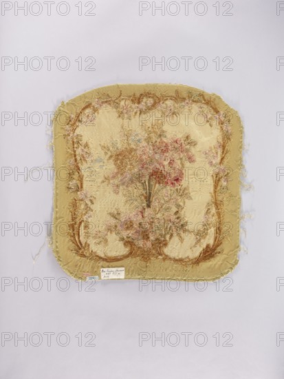 Two tapestry armchair backrest upholsteries and one sofa upholstery, unknown author. Varietal, Flowers, floral ornaments; furniture upholstery, interior furnishings, decorative fabrics, tapestries. a, b armchair upholstery with a bouquet of flowers in the center, surrounded by a frame of acanthus flowers and leaves. c sofa upholstery with a spreading bouquet of flowers surrounded by a frame with acanthus flower and leaf motifs. Colors: sandy background, olive, pink, red, ochre, blue, and green ornaments. 18th/19th century, France. Fabrics. Height 64 cm, width 62 cm., A square textile panel with rounded corners rests on a pale lavender background, showing frayed edges and loose threads; the panel is primarily a muted gold and beige with decorative floral embroidery in shades of pink, dusty rose, faded red, olive green, brown, and hints of pale blue, arranged in a central bouquet and a surrounding ornate border; the stitching appears textured and worn, with a few areas of threadbare fabr...