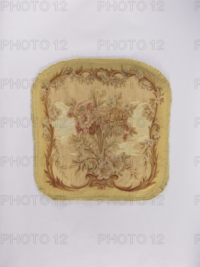 Two tapestry armchair backrest upholsteries and one sofa upholstery, varietal, gift, flowers, floral ornaments, furniture upholstery, interior furnishings, decorative fabrics, tapestries; a, b armchair upholstery with a bouquet of flowers in the center, surrounded by a frame of acanthus flowers and leaves; c sofa upholstery with a spreading bouquet of flowers surrounded by a frame with acanthus flower and leaf motifs. Colors: sandy background, olive, pink, red, ochre, blue, and green ornaments. 18th/19th century, France; fabrics; height 64 cm, width 62 cm., A square fabric panel with rounded corners displaying a central floral bouquet surrounded by an ornate scrolling border; the piece shows woven flowers and leaves in muted pinks, reds, greens, and beige tones set against a golden yellow background with brown decorative accents and pale highlights, and the fabric edges appear slightly frayed.