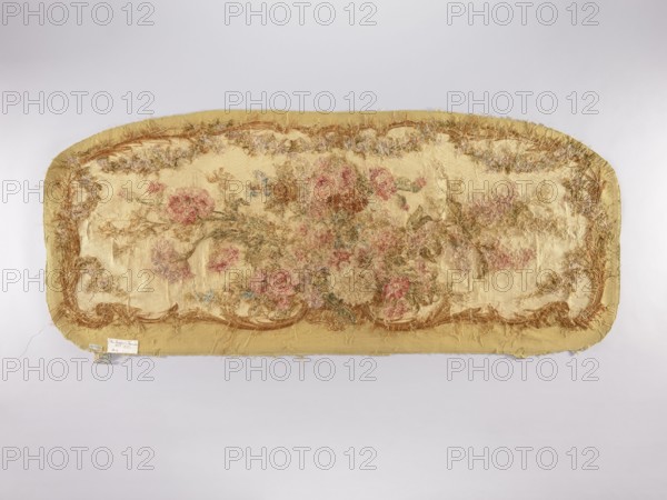 Two tapestry armchair backrest upholsteries and one sofa upholstery; unknown author. Varietal; . Subject: flowers and floral ornaments for furniture upholstery—decorative tapestries. a, b Armchair upholsteries with a bouquet of flowers in the center, surrounded by a frame of acanthus flowers and leaves. c Sofa upholstery with a spreading bouquet of flowers surrounded by a frame with acanthus flower and leaf motifs. Colors: sandy background, olive, pink, red, ochre, blue, and green ornaments. 18th/19th century, France. Fabrics. Height 64 cm, width 62 cm., A long, rounded rectangular fabric panel with frayed edges, predominantly pale yellow and beige in color, featuring a faded floral motif with a group of pink and muted red flowers and greenish-brown leaves clustered across the center, surrounded by a decorative border of brownish-gold and tan threads, with areas of loose, wispy fibers creating a textured, worn surface and small patches of bluish and greyish tones interspersed.