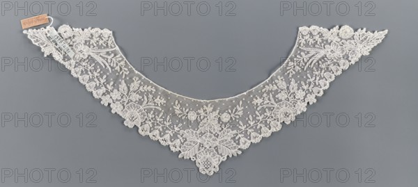 Collar, bobbin lace, 19th century, Europe; women's clothing accessory; width 11 cm, length 34.5 cm. Floral ornament includes various flower rosettes: small 5-leaf rosettes, larger feathery ones at the corners, bell-shaped calyxes with a stripe on the edges, small lanceolate and larger divided leaves., A delicate triangular lace collar displayed flat against a gray background, made of off-white lace with a fine mesh ground and an ornate floral pattern; the scalloped edge is lined with embroidered flowers and leaves, with several larger floral motifs toward the center and smaller sprigs and dotted mesh filling the interior, creating an overall symmetrical, lacy appearance with intricate needlework and a subtle contrast between the off-white lace and the smooth gray backdrop.