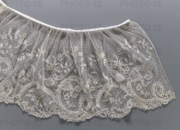 Collar; Lace collar so-called berta with a pattern of flowers, leaves and small dots in the background; floral and plant ornaments; women's clothing accessory; 1840–1860; Brussels place of origin?; lace; width 33 cm., A length of delicate sheer fabric with embroidered floral and scrollwork patterns laid flat against a smooth background; the fabric is translucent with a dotted mesh and ornate lace motifs along the scalloped edge, showing embroidered leaves, flowers, and swirling shapes; the visible colors are shades of off-white and cream for the lace and embroidery, pale beige highlights, a translucent whitish appearance in the mesh, and a muted gray background.
