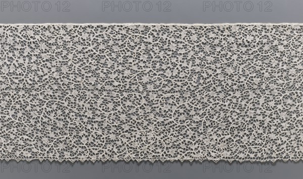 Lace, lace; purchase provenance; with a pattern of twisting floral branches. The de brides type of joining with picots. The lower edge is finished with picot serrations, the upper with a bobbin insert. Probably the bottom of an alb. 17th–18th century, France. Materials: lace, fabric. Width 29.5 cm, length 217 cm., A wide horizontal expanse of delicate openwork fabric with an intricate looping lace pattern in an off-white or cream color laid flat against a smooth medium gray background; the lace shows a dense network of curved threads forming irregular small openings and floral-like motifs with a scalloped lower edge, and the image presents a few subtle shadows where the lace meets the background.