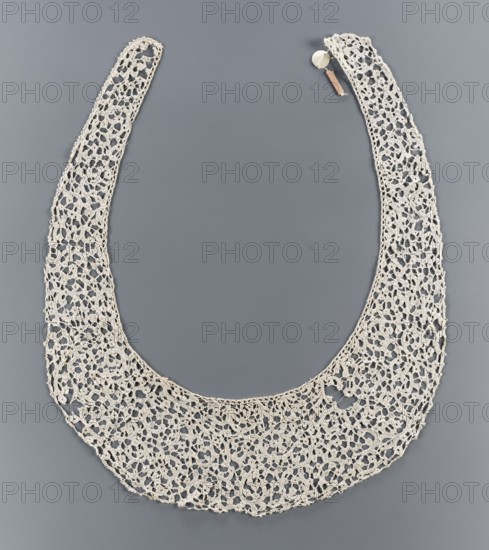 Collar, lace, ribbon pattern imitates a twig or floral sprig. Oval collar with very elongated ends. 17th century, Italy, lace clothing accessory, width 11 cm., A delicate crocheted collar in an off-white color is arranged in a U-shape against a smooth medium-gray background; the collar shows an open lace pattern with a repeating floral-like motif and scalloped outer edge, and a small round fastener with a short pale brown strap is visible near one end.