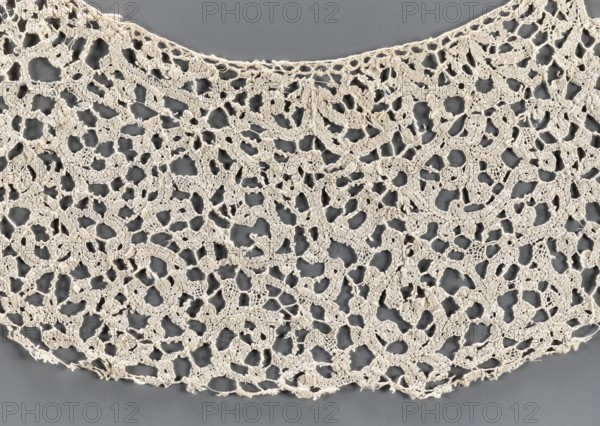 Collar, lace; ribbon pattern imitates a twig or floral sprig. Oval collar with very elongated ends. 17th century, Italy . Lace clothing accessory, width 11 cm., A piece of openwork fabric with an irregular lace pattern lies against a smooth background, showing a network of interconnected loops and floral-like motifs with many open spaces; the lace is an off-white or cream color and the background is a medium gray, with the lace edges curving gently and some loose threads visible along the border.