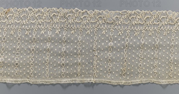 Lace fragment, Alençon lace, lace, At the bottom, an edging ornament running in a clearly separated strip, in the ornament plant motifs and an openwork form resembling the letter S repeated regularly. Higher on the mesh, oval stripes between which projections: small diameter points. 1st half of the 18th century, France. Lace, fabric; width 17 cm, length 206 cm. Unknown creator; purchase provenance., A length of delicate lace fabric displayed horizontally against a smooth gray background, showing an off-white or cream color with intricate patterns; the top edge features a scalloped decorative border with floral and looping motifs, followed by a band of fine netting filled with evenly spaced small raised dots and vertical undulating chain-like lines made of rounded linked shapes, and the bottom edge ends with a narrow embroidered hem with a subtle wavy outline, all textures appearing fine, airy, and lacy with visible openwork and raised embroidery.