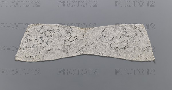 Collar, lace clothing accessory; early 18th century, Binche. Lace, width 15 cm, length 57 cm. Background fond de neige, de brides and others. With large and small floral motifs, ribbons and candelabra., A long, narrow piece of intricately patterned lace displayed flat against a smooth background, showing a floral and scrollwork design with openwork areas and dense embroidered sections; the lace appears off-white or cream with subtle variations in shade, and the background is a uniform mid-gray.