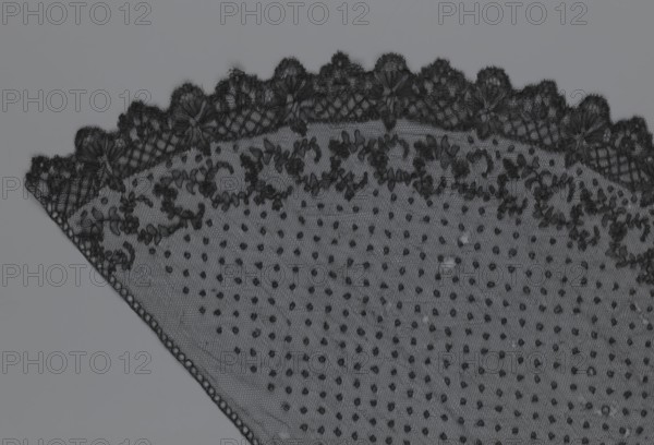 Veil, veils, lace, clothing accessories, fashion. Lace with a floral-geometric pattern running in a wide strip along the semicircular, serrated edge. The remaining part features fond de Tull and regularly spaced small circles. 19th century, France. Clothing; height 35 cm, width 74 cm., A triangular piece of lace fabric occupies the image, showing a scalloped upper edge with intricate embroidered floral motifs and a fine netting background; the main field of the fabric features a dotted pattern of small raised tufts, and there is a narrow woven border along one slanted edge. The visible colors are shades of black and gray.