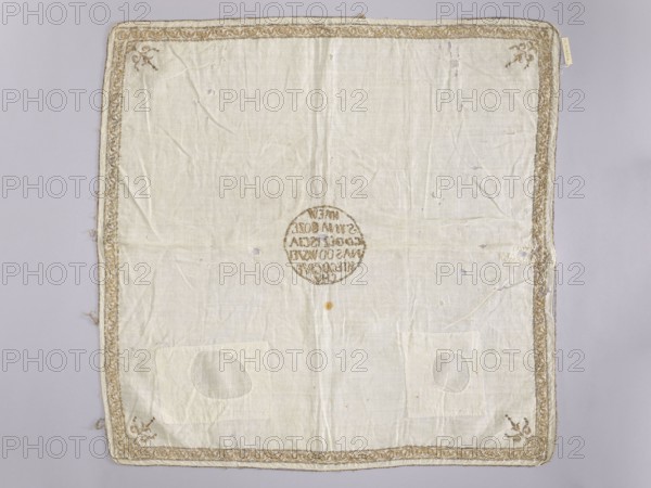 Church napkin made of white batiste density: 34 weft threads and 28 warp threads per 1 cm, embroidered with gold thread on a silk base. Pierced embroidery, in narrow motifs from edge to edge. In the center, in a circle, the inscription: BLOOD / OF THE SON OF GOD / SAVINGS / US FROM ALL SIN. Narrow border with a plant twig motif. In the corners there are stylized bouquets - candelabras. 17th/18th century, Poland. Fabrics. Height 65 cm, width 65 cm., A square cloth in off-white and pale beige tones lies flat against a light gray background, showing creases, small holes, and a few faint stains; its edges are trimmed with an ornate braided border in a gold-beige color with decorative corner motifs in the same hue; near the center is a circular embroidered motif in a darker tan color; two patch-like rectangular areas with oval repairs are visible toward the lower portion; the fabric texture and stitching are discernible across the surface.