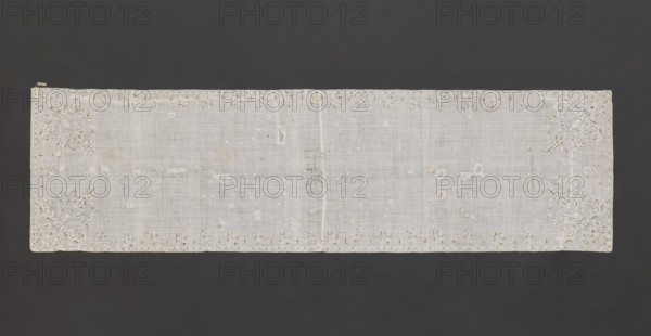 Church napkin. Napkin of white, thin, sparsely woven plain-weave batiste, embroidered with silk thread and metal threads on a silk base; fabric sewn together in the center. Embroidered motifs of small floral sprigs and stars along the long edges; corners feature larger stylized flower bouquets emerging from a single stem. Embroidery mainly in white threads, details in metal threads. One end bears an embroidered inscription: Katarzyna z Obory Oborska / AD. 1636. In the center, within a frame, a partially illegible embroidered inscription: BODY M.../.../AND MY TRUE BLOOD/IEST..../WHO WILL FEED. Flat embroidery with silk yarn and pierced metal threads; stitches include satin and cord. Metal threads: cut copper-gold plate and silver-gold plate woven on a silk core. 17th century, Poland. Fabrics; height 236 cm, width 64 cm., A rectangular piece of translucent fabric laid flat against a dark background, primarily white in color with subtle variations in tone; the fabric shows a woven texture...