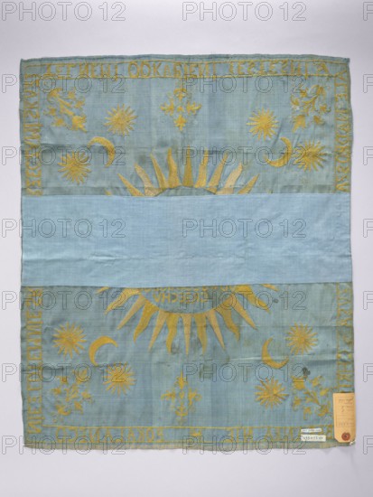 Church napkin. Blue silk rep cloth embroidered with gold thread. In the center, within a radiant halo, a sun with an inscription in Polish: THE BLOOD OF OUR LORD JESUS IS CHRIST, WHICH PURIFIES US FROM ALL SIN. Corners bear stylized Eastern-style bouquets of flowers, crescents, and stars; similar bouquets at the midpoints of each edge. Along the edges, an inscription in Polish: NOT WITH GOLD, NOT WITH SILVER, NOT WITH THINGS CONTAMINATED, WE REDEEMED YESTESMI, BUT THE BLOOD OF JESUS CHRIST, THE UNDAMAGED LAMB. Resplendent fabric density: 36 weft threads and 29–32 warp threads per cm. One workshop edge preserved, the other cut. Embroidery with gold thread on a yellow silk ground laid stitches, stitched with yellow silk thread. 17th/18th century, Poland. Height 67.5 cm, width 57 cm., A rectangular fabric with a pale blue background features golden embroidered decorative elements including a large central sun with radiating rays, several crescent moon shapes, and multiple stylized stars o...