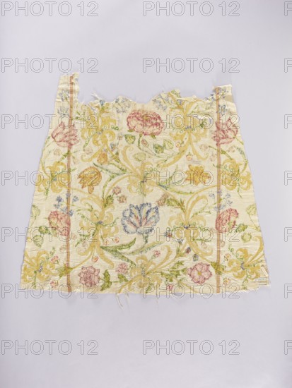 Two fragments of a dalmatic, front and back, of silk fabric interwoven with silver thread. The embroidered decoration consists of a floral tendril with tulips, bellflowers, pansies, carnations, daffodils, irises, and roses with species-accurate leaves, alongside golden fantastical flowers with bent stems. Predominant colors: yellow several shades, blue, pink, red, green, and gold. Embroidery: metal thread gilded silver plate woven on a silk base and multicolored silk; gold embroidery executed with a laid flat stitch, metal threads secured with silk yarn; silk embroidery in satin and split stitches. Fabric: silver lamé grosgrain interwoven with silver thread; gauge width 50.5 cm, yellow-red selvedge; density 17–18 weft threads per cm², 14–15 warp threads per cm². Embroidery dated 18th century; fabric dated 16th century. Places of origin: embroidery — Poland; fabric — Italy. Liturgical vestment dalmatic. Length 104.5 cm, width 87 cm., A rectangular piece of fabric with frayed edges and a...