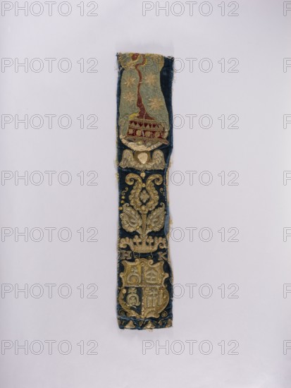 Chasuble pillar, embroidery, liturgical vestment, coats of arms, Lubicz coat of arms, Radwan coat of arms, Lis coat of arms, flowers, leaves, plant ornaments, church paraments, sacred art, churches and chapels furnishings. Chasuble pillar embroidered on dark blue velvet. At the top is a depiction of Mary cut off part with the figure's head; below is a winged angel's head and a stylized flower bush growing from a crown. Under the crown are the letters H and K and a four-field coat of arms with the coats of arms: unrecognized, Lis, Lubicz, and Radwan. Embroidery on velvet and linen canvas, laid with metal threads on a backing of linen yarn. A fragment of burgundy velvet is applied to part of Mary's dress. Metal threads: cut plate in silver and gold, plate woven on a silk cord, gold and silver wire, gold and silver bullion. Mary's cloak features a linen cord tightly wrapped in blue silk yarn and gold wire. The angel's hair features a metal wire wrapped in silk yarn and gold wire. Silk yar...