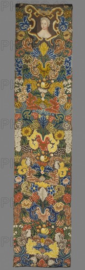Tapestry, Tapestry embroidered in wool and silk on linen canvas. In the upper part, within a decorative cartouche, is the bust of a woman with a full face and high forehead, framed by curls forming a slightly raised hairstyle. Around it are dense scrolls of large leaves, flowers, and fruit. No border. Vivid colors: brown background, sapphire blue, navy blue, green, yellow, pink ornaments. The plant motifs of the nine fabrics comprising this set do not differ from each other. Stylized leaves, flowers, and fruit fill the entire surface of the panel. The composition unfolds on both sides of the axis, defining a symmetrical division of the decoration, similar to the large-pattern silk upholstery fabrics fashionable in the late 17th and early 18th centuries. Minor differences include the inclusion of small animal silhouettes on some panels. All fabrics are decorated with the same fruit: plump bunches of black and white grapes, yellow apples, and dark red cherries. Vivid colors, brown backgr...