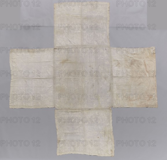 Church napkin, church paraments; Evangelical churches furnishings; floral motifs; Sereje Lithuania; flowers, leaves, plant ornaments; sacred art; churches and chapels furnishings. Rectangular church napkin 113 x 123 cm, from which four others branch 86 x 57 and 57; 89 x 53 and 53. Made of white linen canvas, embroidered with white thread with motifs of large, stylised floral bouquets in the Eastern style, between which are smaller flowers; sewn with an insert of bobbin lace and trimmed with bobbin lace. The side rectangles are sewn from two pieces joined with lace; the middle one is also sewn together, but joined with embroidery. The embroidery motifs are similar to those on a napkin dated 1636. Lace: 17th century, ca. 1636, Poland. Fabrics. Height 314 cm, width 297 cm., A large cross-shaped textile made of a light fabric displayed flat against a gray background, with a central square panel and four rectangular extensions; the fabric is off-white to cream with areas of discoloration ra...