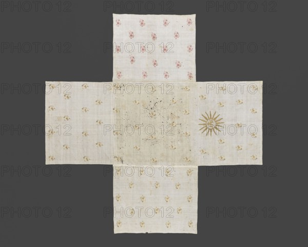 Church napkin. Church napkin of thin white linen sewn from five rectangular pieces of fabric in the shape of a cross. Embroidered with evenly spaced projections of stylized floral sprigs in gold, dark pink, and straw. One side rectangle bears an embroidered gold IHS monogram within a halo; on the opposite rectangle, on the edge, is the inscription ANNA Z RUSOCKICH ORZECHOWSKA. R. 1743. Dated 1743. Maker: Anna Orzechowska née Rusocka 18th century; fl. ca. 1743. Function: church paraments/evangelical church furnishing. Subject: flowers, leaves, plant ornaments, sacred art. Material: fabrics thin white linen. Place of origin: Poland. Dimensions: height 290 cm, width 290 cm., A cross-shaped textile composed of pale off-white fabric panels laid against a dark gray background, with a few small floral motifs in muted pink and faded yellow scattered across the panels; the central area appears slightly darker and more stained with a few dark speckles, and one arm of the cross shows a sunburst-l...