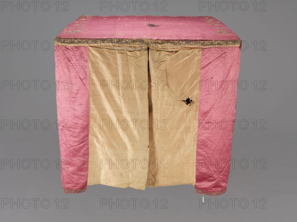 Church cope, liturgical vestment, raspberry satin embroidered with floral patterns. On the front, branch patterns arranged in six rows: two types—asymmetrical, slightly inclined branches with three flowers, and symmetrical, straight branches with a single flower at the top and two pairs of leaves. Edges decorated with a border of floral and fruit tendrils; lower edges trimmed with gold bobbin lace. Beige linen lining. 17th century, Poland. Height 298 cm, width 201 cm., A rectangular cloth structure with a top and front panels is shown, the top and side front panels are pink with a slightly shiny texture and decorative trim along the top edge, and the central front panels are beige with visible creases and a tear in one panel; the fabric appears worn and slightly stained in places, and the background is a uniform gray.