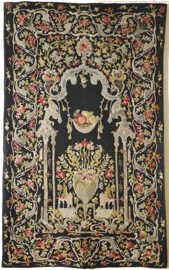 Tapestry, In the center, in an architectural frame modeled after Eastern styles with Rococo elements, is a vase of flowers, flanked by sections of fantasy architecture with an Eastern line. Above is a hanging basket of fruit. The border consists of floral tendrils. Predominant colors are black background with sand, blue, and pink ornament. Appliqués are made of fragments of sparsely woven woolen fabrics; edges of appliqués are embroidered with a needle and silk thread. Some motifs are embroidered with gold thread. Tapestry embroidered and appliquéd with silk and metal threads on a dress, Syria-Damascus, 18th century. Similar 18th-century examples attributed to Syria or Turkey; such tapestries were produced in places like Banja Luka, Bursa, and Istanbul and were intended to decorate tents. Dimensions of a comparable example: height 224 cm, width 142 cm., A large rectangular textile with a dark background covered in an elaborate embroidered design featuring flowing vines, stylized floral...