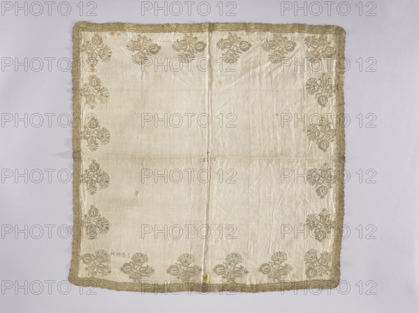 Velum, embroidery, church paraments, floral motifs, Henryków German: Heinrichau. Flowers, leaves, plant ornaments; sacred art; churches and chapels furnishings. Velum or church cloth of white linen batiste, embroidered along the edges with floral bouquet motifs in gold thread. In the center is an embroidered inscription IESUS, above which a small cross. Around the edges are stylized Persian-style flower bouquets. In one corner are embroidered the letters HHGS. Trimmed with gold bobbin lace with an interwoven ribbon motif late 17th century. A wide approx. 3 mm strip of gold thread is sewn onto the edges where the lace is sewn. Double-sided embroidery. Flat, pierced embroidery, satin stitch. Stitch direction is adapted to the shapes of the ornaments. Metal threads — a gold plate covered with multicolored patina, woven on a silk base. 17th century, Silesia; liturgical vestment. Height 74 cm, width 82 cm., A square fabric laid flat with a pale cream background and a border of gold trim; th...