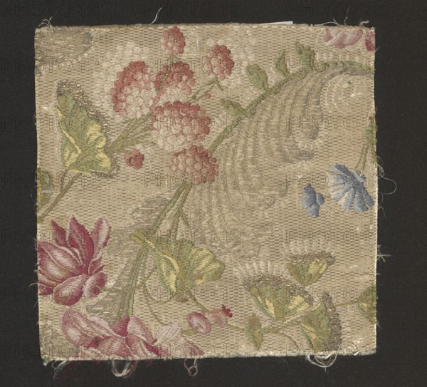 Fabric fragment, silk, 18th-century France. Background: cannetillé white; brocaded pattern in celadon yellow, white, sky blue, paint, green-olive, light green, rose-burgundy, rose-orange, pale pink, red, and gold lamella. Pattern: flower branches with umbrella-shaped leaves; flowers reminiscent of cornflowers, raspberries, and peonies. Dimensions: 19 cm × 19 cm., A square textile sample with a beige woven background featuring a floral pattern in muted colors, showing a group of pinkish-red clustered blooms, several green leaves with yellow accents, a few blue petal shapes, and larger rose-like flowers in shades of pink and red; there are subtle metallic thread highlights in parts of the leaves and scroll motifs, and loose threads along the edges; the piece is set against a dark background.