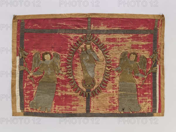 Antependium, antependium;, Raised embroidery applied to red silk satin: in the center Mary and Child in radiant glory on a crescent; at the sides two angels holding lilies. Trims of silver; 17th-century galloon. Embroidery on linen backings of varied heights, applied to silk satin; silk thread split stitch for body parts, metal thread laid stitch for other elements. Metal threads in gold and silver: cut plate, plate woven on linen base, drawn wire. 17th century, Poland. Fabric; height 85 cm, width 126 cm., A rectangular textile with a worn deep red background bordered by tan and dark gray bands, featuring a central oval medallion outlined in tan and dark gray with a figure inside rendered in faded gold and gray tones, flanked on either side by a pair of standing winged figures made of similar gold and gray stitched fabric holding stylized branches, all showing areas of fraying and threadbare wear that reveal lighter tan patches and underlying fibers.