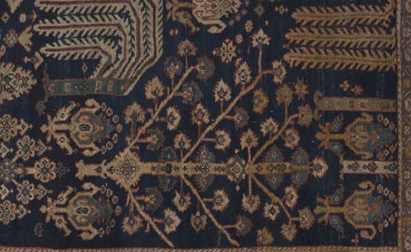 Carpet, The main field is filled with motifs of various species of trees arranged in three vertical rows; between the trees are flower bushes, palmettes, and small rosettes. Seven-strip border with plant ornament. Colors: navy blue, red, yellow, cream, navy blue, blue and red. Rectangular section contains stylized weeping willows, cypresses, flowering trees pomegranate, lotus palmettes. 19th century, Iran; cotton warp, symmetrical wool knots; density approx. H27 x W26 ˜702 knots/dcm2. Height 512 cm, width 430 cm., A woven textile with a dark navy background patterned with a repeating botanical motif in shades of beige, tan, rust, olive green, muted teal, and light blue, featuring branching stems with stylized flower shapes and geometric medallions, bordered by bands of ornate design in similar colors and a narrow fringe edge.
